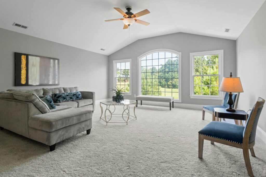 A spacious living room featuring a comfortable sofa, stylish chairs, and large windows overlooking greenery.